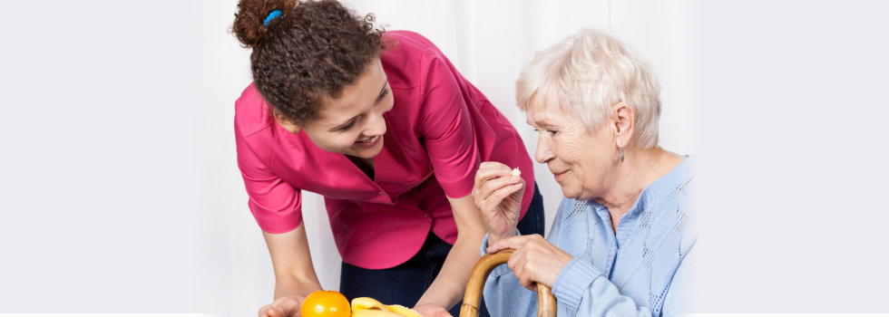 caregiver serving meal for elderly woman